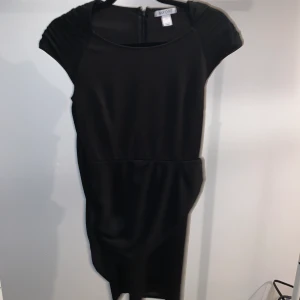 Klänning från Nelly - En figursydd klänning från Nelly med meshtyg vid axlar. Meshtyg hänger runt klänningen. Klänningen är S men passar Xs också 