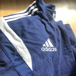 Adidas  - Blå tshirt mkt fint skick. Tre streck och två bredare över.Storlek M vet ej dam eller herr, passar både tjejkropp och tvärtom! Köptes för ca 300! Allt ska bort så passa på 