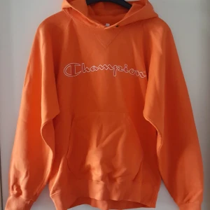  - Orange Champion tröja i storlek S, skulle tro att den nog passar M också. Finns en liten fläck nedtill på ena ärmen (se bild 2) och snöret är borttaget. Den är inte fullt lika mörkt orange som på bilderna. Fraktkostnad blir 88kr.