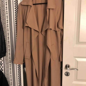  - Beige tunn kappa som e super fin till våren, kommer tyvärr inte till användning hos mig längre, frakten är in räknad i priset, en hållare har gått söder som ni ser på bild 3 men den går att sy fast igen, finns även ett band till, frakten är inräknad 
