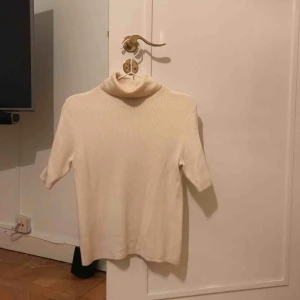  - Kortärmad ribbad tröja med polokrage (gräddvit). Sticks ej