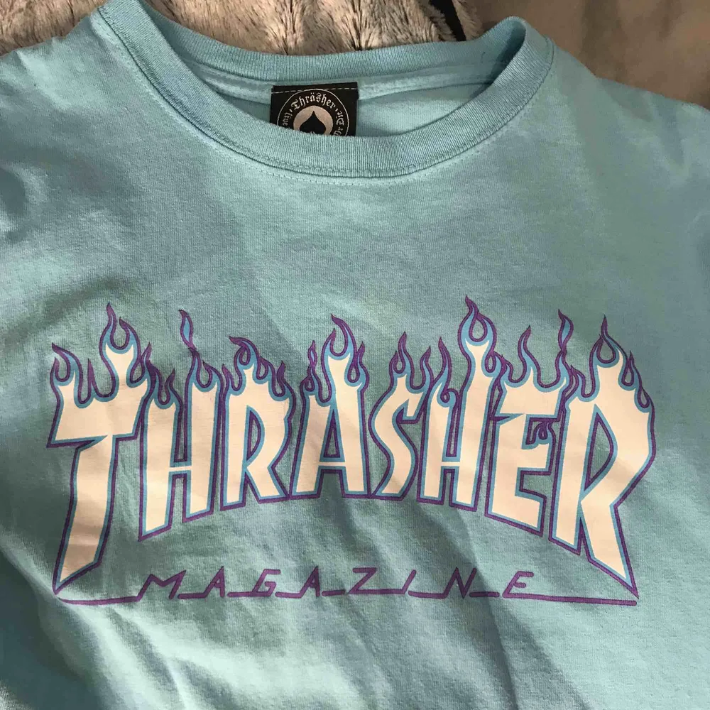 Ljusblå thrasher T-shirt med lila flammor. Mycket bra skick knappt använd . T-shirts.