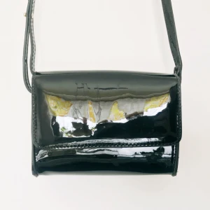  - Liten axelremsväska i lack. Aldrig använd.  Lapp försökt till bortklippt inuti pga. i vägen.  Ca. L20xH10cm.  100kr + 30kr i frakt. Betalning via Swish. 