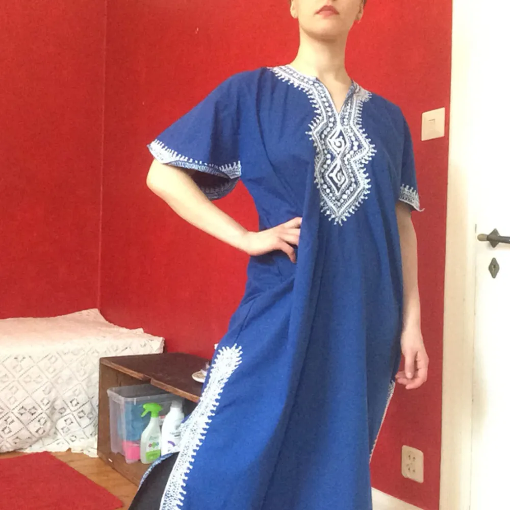 A beatiful blue dress with unfortunately unknown origins, since I have owned it for years and years. Detailed white patterns. Frakt +50kr. Klänningar.