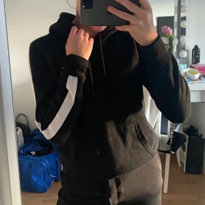 Svart hoddie - Svart hoddie med en vit linje på armarna. Säljer pågrund av att den inte kommer till användning! Storleken passar även i S! Pris kan diskuteras 💕