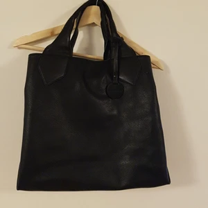 Skinnväska - Svart skinnbag inköpt i Berlin. Stor och rymlig, stängs med dragkedja och knäppe vilket gör skillnaden mellan bild 1 och 2. Bra skick, inga repor eller annat.