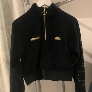 Ellesse croppad tröja i velvet  - Croppad velvet tröja från Ellesse i gulddetaljer. Dragkedja i guld och guldig text med elesse på vänsterarm. Använd fåtal gånger och i bra skick! 