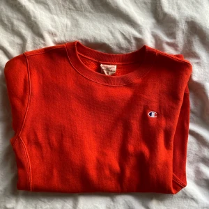 Champion crewneck - Säljer min älskade champion crewneck då den inte längre passar med resten av min garderob. Har aldrig fått så många komplimanger för färgen på ett plagg som jag fick när jag hade på mig denna orangeröda crew. Den är i storlek M och passar en S/M. Originalpris 800kr. Säljs i befintligt skick. Fraktkostnaden är inkluderad i priset.