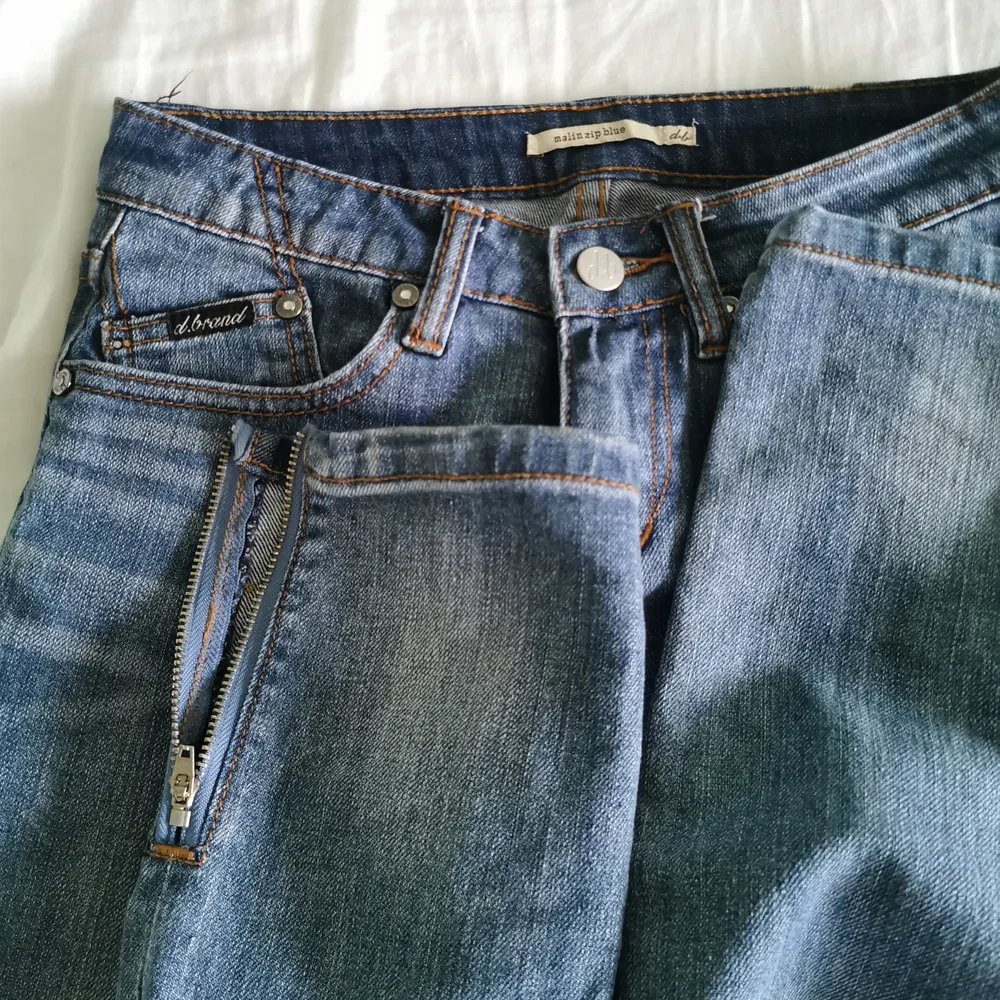 Blåa jeans köpta på NK, med snygga kedjedetaljer och broderat märke på ena bakfickan, d.b. Kedja vid benslut,  så man kan välja och ha slits eller inte. Skriv för fler bilder/frågor  Har garderobsrensning så kolla gärna in mina andra annonser för paketpri. Jeans & Byxor.