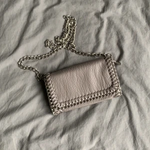 Beige/grå liten väska  - Liten väska med silver detaljer ifrån scorett. Använd få gånger, mycket fint skick! 