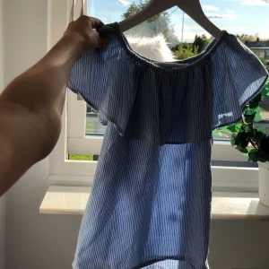 Blå o vit randigt blus  - Fin randig vit och blå blus från Lindex. Går och använda som off shoulder. Perfekt till sommaren. Köparen står för frakt.