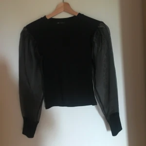 Zara topp - Festlig svart topp från Zara med ”puffärmar” gjorda i mesh material. Använd endast en gång 