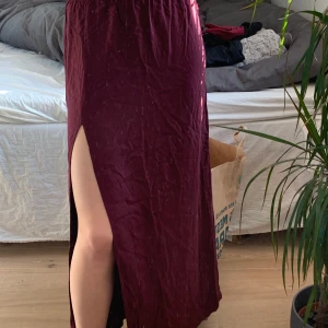 Vinröd Gina Kjol - Jättefin vinröd långkjol, slit på ena sidan, kommer tyvärr inte till användning, dragkedja i bak som ni ser på sista bilden❤️