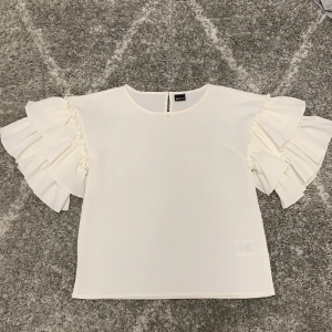 Vit stilig blus med volanger vid ärm - Fin stilig blus med volanger vid ärmarna. 