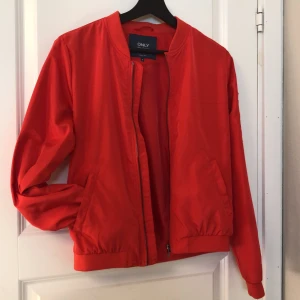 Röd jacka - Röd jacka i  ”bomber” modell. Tunn och därför perfekt till sommaren. Aldrig använd, märker only. Storlek M men lite liten på mig så skulle säga att den även passar S