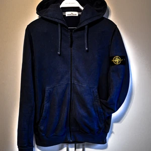  - Stone Island-hoodie som passar både M och L. Den här modellen har två stycken framfickor som har Dragkedja vilket jag insett är ett måste nu när jag haft det. Tröjan är i bra skick och är självklart äkta. Det finns en CLG-kod/QR-kod i tröjan som visar att den är äkta som efter förfrågan kan skickas. Tröjan är i en väldigt mjuk mörkblå och passar till nästan alla kläder! Kan mötas upp och frakta :D