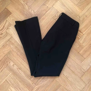  - Kostymbyxor med liten ut svängning nedtill. Använda en gång. Två detalj fickor baktill. 