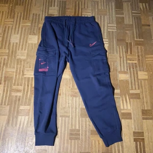 Nike - Säljer en Nike tracksuit (tröja och byxor).                           Storlek M på byxorna och Storlek M på tröjan. Det är ett par cargo byxor/mjukis. Har använts 1 gång. Om du har några frågor så är det bara att skriva. Säljer både tröjan och byxorna tillsammans för 900kr men de kan diskuteras.