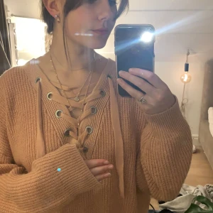 Stickad tröja  - En rosa stickad tröja med snörning från H&M, i fint skick. Frakten ingår inte.