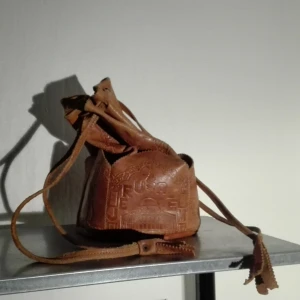  - Round leather bag from Jerusalem covered with carved images and small pockets on the sides. Also kinda Discreetly says Jerusalem on one side.  Bought at secondhand but well kept.   Buyer pays for shipping, 42 Swedish kroner. 