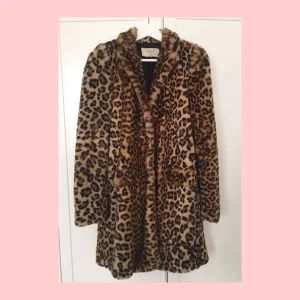  - Lång leopardmönstrad kappa i fuskpäls. Två fickor fram.  Något sliten och nopprig i pälsen, så som fuskpäls blir efter ett tag, samt ett brännmärke, men som inte syns pga mönstret. Därav det billiga priset :) 
