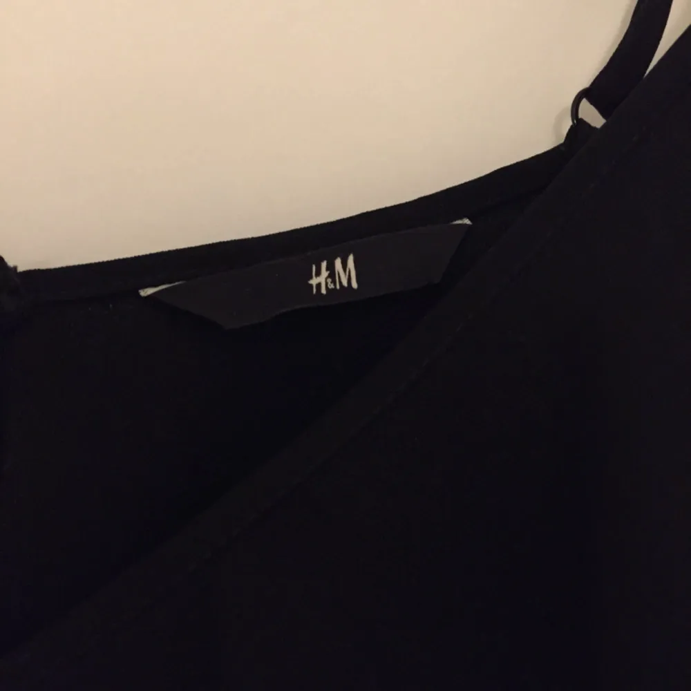 Fin jumpsuit i svart från H&M, avsmalnande ben och smala axelband. Dekorativa volanger fram. Använd ett fåtal gånger, är i fint skick. Köparen står för frakten. Jeans & Byxor.