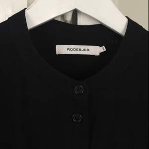Rodebjer shirt dress art storlek XS. Dock stor i storleken, jag har alltid S/36 annars. Superfint skick, använd endast ett par gånger. The Rodebjer Art is a versatile ankle length shirt dress in a soft viscose fabric. It can be worn buttoned, as a shirt-dress, or open as a light coat. It can also be wrapped around the body or draped in various ways.  Color: Black. Front, sides and back button closures. Band collar. Ankle length Wear as shirt/dress or open as light coat. Can wrap around body in various ways.