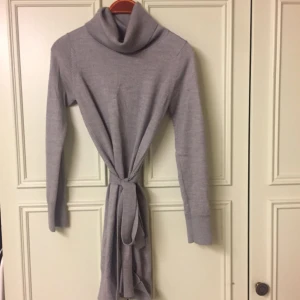  - Väldigt väl vårdad klänning i 50% ull och 50% akryl som sticker inte och är behaglig mjuk. Polokrage som faller mjuk och liten skärp i midjan. Sitter nära kroppen och storleken M är mycket optimistisk, den passar inte M men till en Small size.  Längden på framsidan är 75 cm. Mycket fint skick, inte alls nopprig och från djur- och rökfri hem.