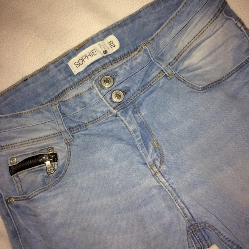 Sköna ljusa Sophie-jeans från Ginatricot, med lite tvättade/blekta detaljer i tyget. Dragkedja på bakfickorna och på en liten ficka fram. Är i ganska gott skick, men det är hål under två 