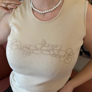 Beiget y2k linne med tryck  - Trendigt y2k linne med tryck i neutrala färger🤎. Personen på bilderna bär oftast medium och är 173 cm lång. Plagget är second hand men sparsamt använd! Köparen står för frakt. 