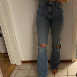 Utsvängda jeans med hål i knäna. Köpta från Gina Tricot. Använda några gånger, jättesköna och stretchiga. Strl 34.