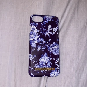 Skal från ideal of sweden till iPhone 7/8  - Säljs pga ny mobil. Jättefint blått blommigt skal. Lite repigt pga använt. Frakt tillkommer. 