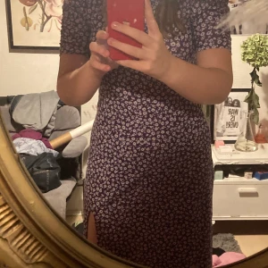 Lila superfin klänning.  - Lila lite lägre klänning med blommor köpt på h&m. Använd cirka en gång. Köparen står för frakten💎💎Har även samma modell i svart med blommor på om någon är intresserad. 