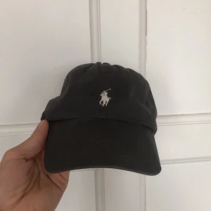 Ralph Lauren keps - Grå keps från Ralp Lauren. Fint skick!! Säljes då den inte riktigt passar mig. Köparen står för frakten. 