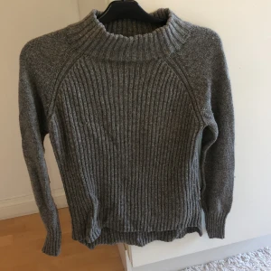 Stickad tröja från LINDEX - Mysig, långärmad stickad tröja från Lindex. Storlek S, men en liten polokrage. Längre baktill. Tröjan är i gott skick.