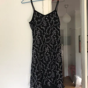 Svart, blommig klänning - Superfin, svart-blommig klänning! Går ner till ovanför knäna på låret och sitter tajt! Fin! 
