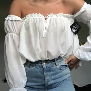 Fin vit topp i offshoulder-modell. Aldrig använd, lappen sitter kvar. Storlek S/36. Frakt 63kr.