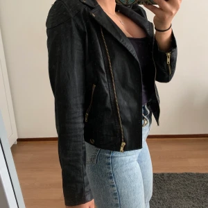 Jacka - En supersnygg skinn jacka som inte är gjort av skinn. Är i färgen svart & har detaljerna är guld