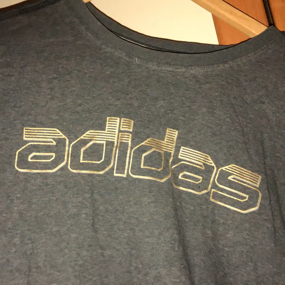 En grå t-shirt från Adidas. I storlek L, ganska bred men inte så lång. Köpt secondhand men i väldigt bra skick. T-shirts.