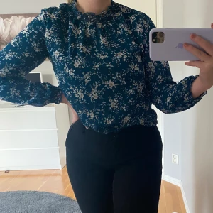 Blommig blus - Säljer en blå blus med blomdetaljer. Tröjan är i storlek S och säljs för 50kr+frakt