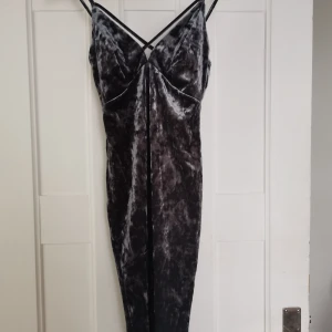 Klänning i sammet  - Blå/grå tight klänning i krossad slammet med kors över urringningen. Använd en enda gång så den är så gott som ny! Frakt ingår i priset! 