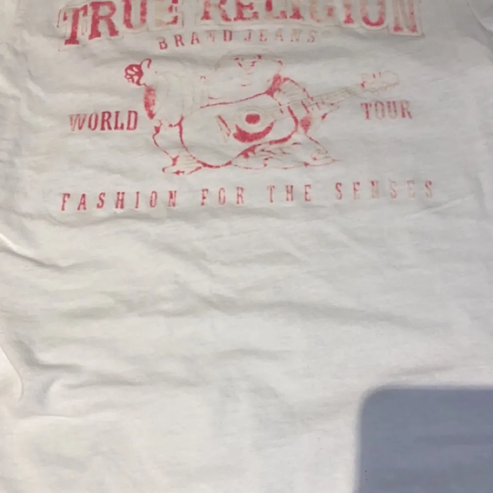 En vit T-shirt från true religion, använder den ej då jag inte gillar rosa, trycket på baksidan är lite förstört av tvätten men det ser lite coolt ut, köparen står för frakt . Skjortor.