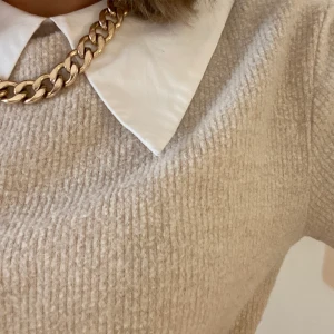 Ribbad Zara topp - En supersnygg och praktisk kortärmad beige topp från Zara med inbyggd vit krage för att få lager på lager looken. Passar perfekt till allt och är i fint skick. Släng på ett halsband och ha den till skolan eller klä upp den vid finare tillfällen.