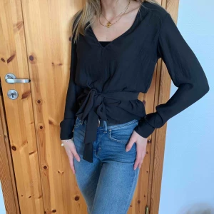  - Mörkblå blus med band till som man kan knyta antingen i midjan eller runt halsen. Ganska liten i storleken, passar XS. Köparen står för frakten.