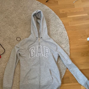 Gap hoodie med dragkedja  - En snygg grå hoodie med dragkedja ifrån GAP. Mycket fint skick och inte använd många gånger alls pga för liten för mig. Köparen står för frakten🥰