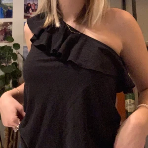 One shoulder topp strl:xs - Svart one shoulder topp med en liten volang. Strl:XS. Från H&M.                                           Fraktkostnaden står köparen för!😊