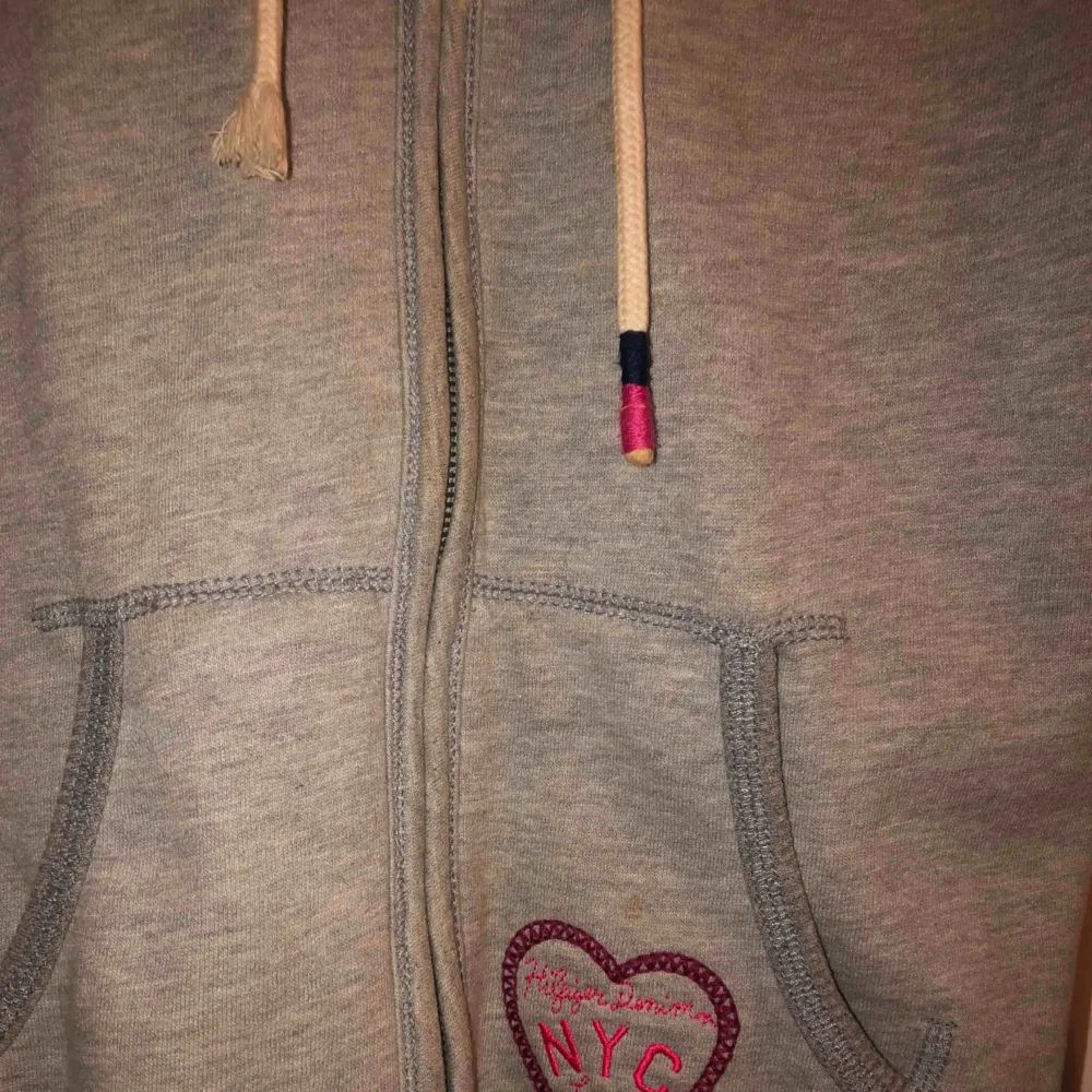 Jättefin hoodie med dragkedja framtill från Hilfiger Denim. Köpt på Tommy Hilfiger i Stockholm för 1300kr. Jätteskön luva med foder (fuskpäls). Jättefint skick, ena snöret är dock skadat (sista bilden) . Hoodies.