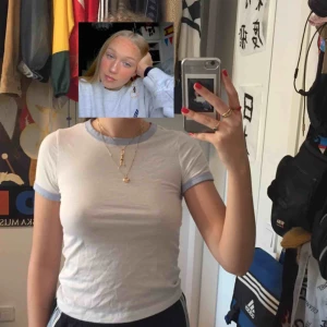  - Vit t-shirt. Ljusblå runt halsen och armarna