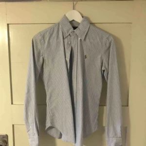  - Ralph lauren skjorta. randig i blå och vit. Knappt använd, storlek 4 men som en s/XS. 