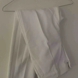  - Vita kostymbyxor med gulddetaljer. 